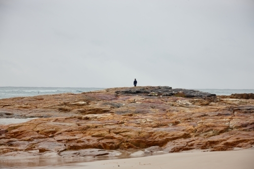 Lone person at coastal landscape on sunrise - Australian Stock Image
