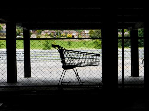 Lone shopping trolley in dark supermarket parking area