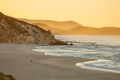 Lone walker on rugged coastline - Australian Stock Image
