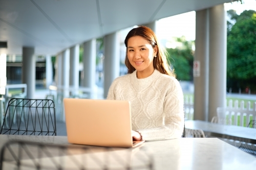 Lone woman working on laptop in seated area - Australian Stock Image