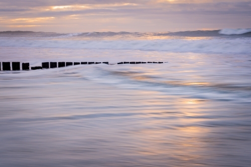 Long exposure of waves rushing along a beach at sunrise