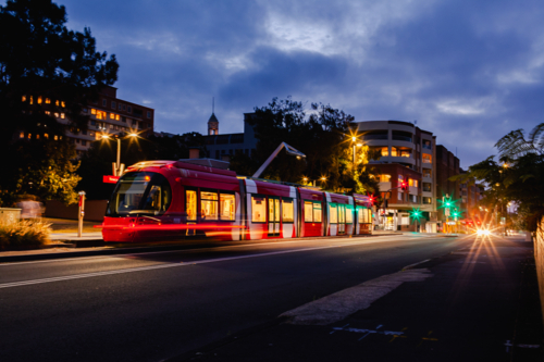 Long exposure red light rail train waiting at Newcastle Beach stop tram station at night  - Australian Stock Image