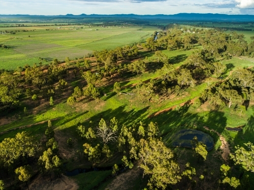 Long shadows over paddock with green grass and rain clouds - Australian Stock Image
