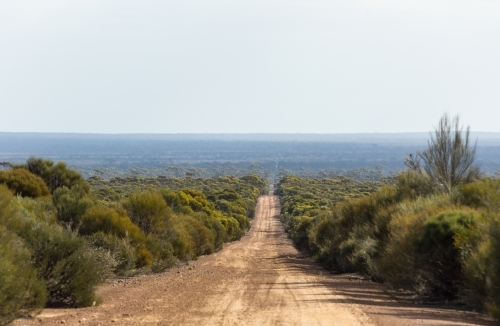 Long straight unsealed road in isolated rural area