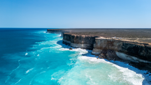 Long stretch of towering cliffs with deep turquoise waters. - Australian Stock Image