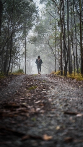 Long view of woman walking through foggy mountain track - Australian Stock Image