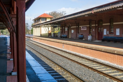 Looking a long the edge of an empty railway platform of a rural railway station - Australian Stock Image