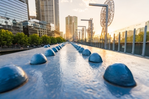 Looking along the steel girders and metal sculptures of the Sandridge Bridge in Melbourne at sunset. - Australian Stock Image