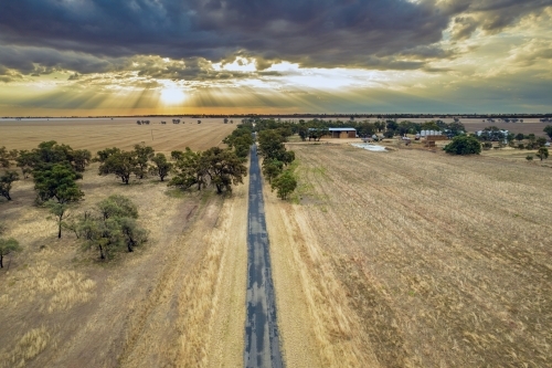 Looking down along the road with the sun setting behind the clouds - Australian Stock Image