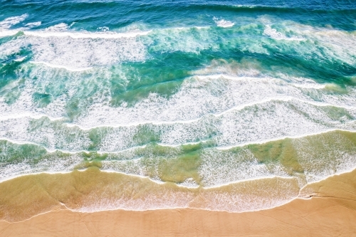 Looking down at ocean colours as the water flows into the sand. - Australian Stock Image
