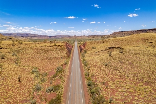 Looking down at straight asphalt road at the red terrain earth - Australian Stock Image