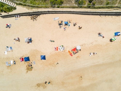 Looking down on a beach sandy beach at umbrellas, towels and beachgoers