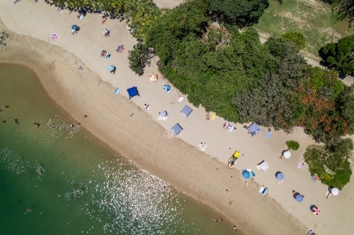 Looking down on a busy beach goers day between the water and trees - Australian Stock Image