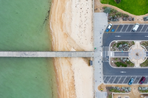 Looking down on a car park leading out onto a narrow jetty over a beach