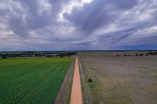 Looking down on a dirt road with the storm clouds on the horizon. - Australian Stock Image