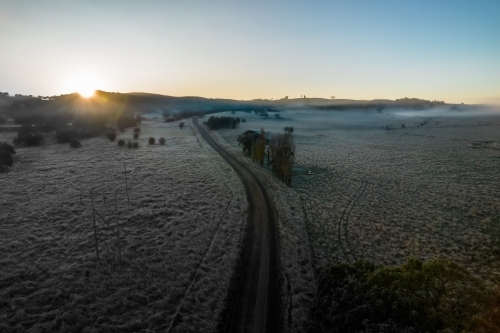 Looking down on a frosty morning the country side with a road leading into the distance - Australian Stock Image