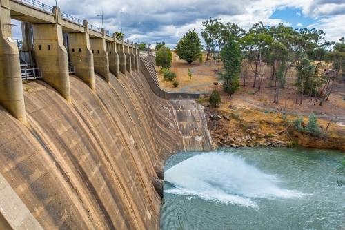 Looking down on a jet of water squirting from the bottom of a dam wall of a reservoir - Australian Stock Image