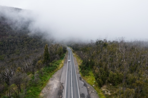 Looking down on a mountainous rural road on a cold foggy morning - Australian Stock Image