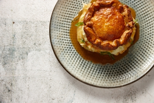 Looking down on a plate of gourmet pie, mash potato and gravy - Australian Stock Image