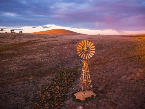 Looking down on a windmill in a dry paddock with a mountain on the horizon