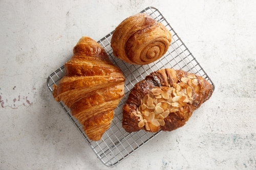 Looking down on three pastries on a cooling rack on marble background - Australian Stock Image
