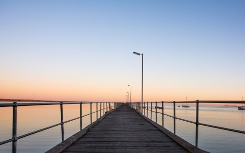 Looking down the pier towards the end of the horizon at dawn - Australian Stock Image