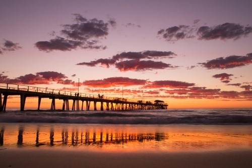 Looking out at a long wharf on the beach at sunset - Australian Stock Image
