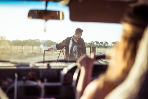 Looking out of car window to person holding open paddock gate - Australian Stock Image