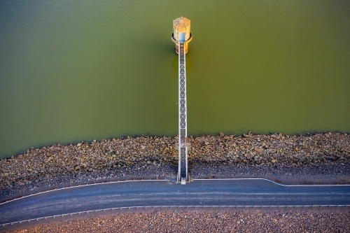 Looking straight down on a water tower connected to a dam wall by a steel walkway - Australian Stock Image