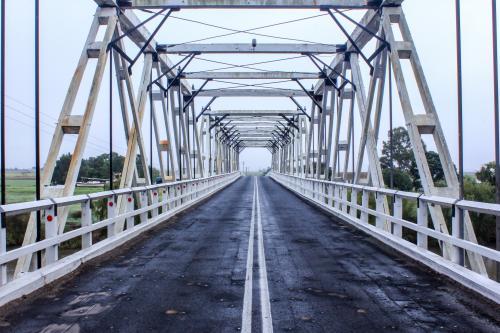 Looking through and across white timber rural traffic bridge - Australian Stock Image