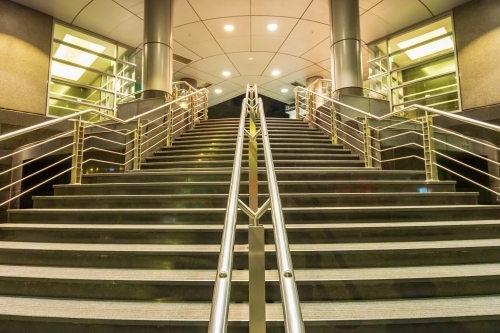 Looking up a staircase with stainless steel railings leading into a modern building - Australian Stock Image