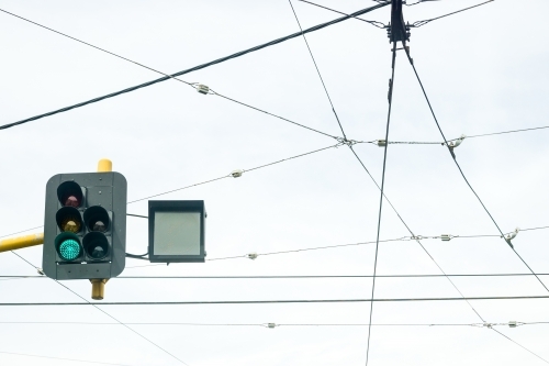 Looking up at a set of traffic lights amongst overhead tram cables