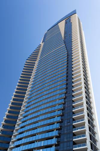 Looking up at a single tall high rise building against blue sky - Australian Stock Image