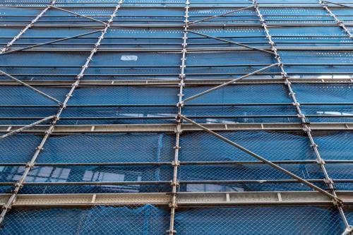 Looking up at city building covered in scaffolding and blue - Australian Stock Image
