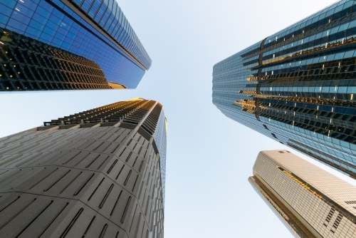 Looking up at converging tall city buildings with reflections - Australian Stock Image