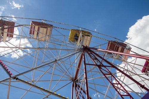 Looking up at ferris wheel in blue sky with clouds - Australian Stock Image