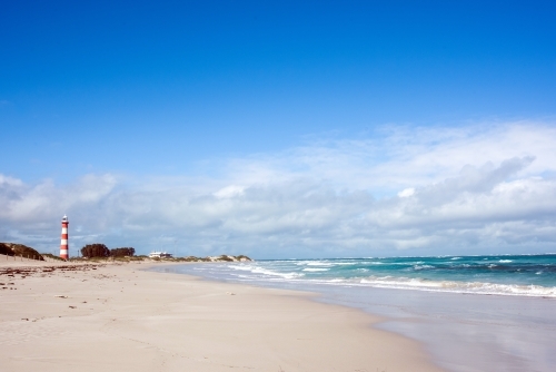 Looking up the beach and seeing a vintage lighthouse in the distance - Australian Stock Image