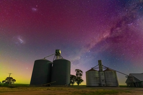 Low angled view of colourful Aurora Australis over banks of rural grain silos - Australian Stock Image