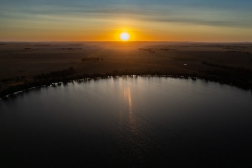 Low sun over landscape with lake in foreground - Australian Stock Image