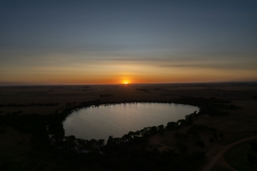 Low sun over landscape with lake in foreground - Australian Stock Image