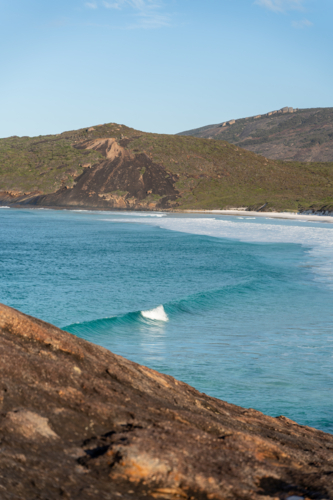 Lush green hills along the coast with turquoise waves rolling to the shore - Australian Stock Image