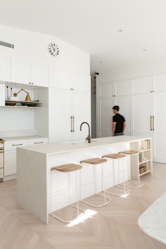 Luxurious high end designer white kitchen with a man walking past