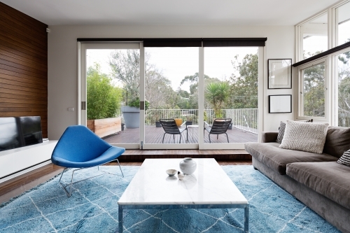 Luxury scandinavian styled living room with outlook to terrace and gum trees - Australian Stock Image