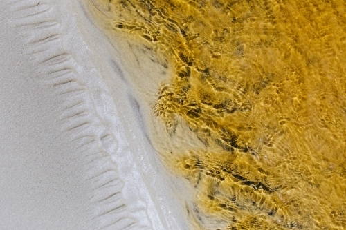 Macro close-up of patterns in the sand and stream with tannins in the water