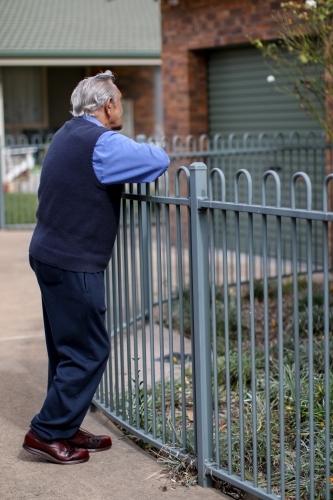Male Aboriginal elder leaning against a fence - Australian Stock Image