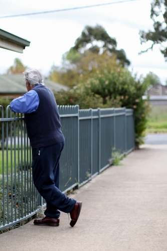 Male Aboriginal elder leaning against a metal fence - Australian Stock Image