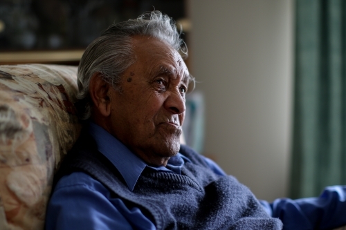 Male Aboriginal elder sitting in an armchair in his home - Australian Stock Image