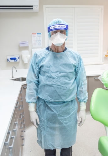 Male dentist wearing PPE in dental practice - Australian Stock Image