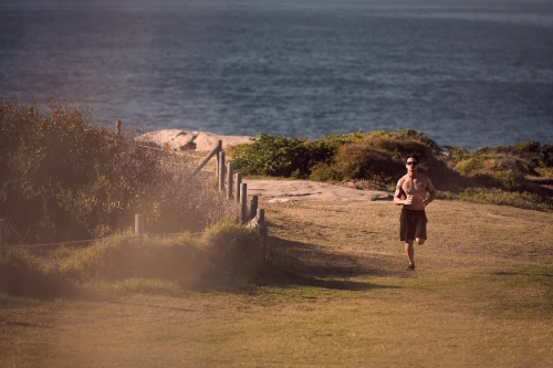 Male exercising on a morning run beside the ocean - Australian Stock Image