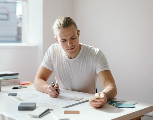 Male interior designer choosing colours and finishes for a project - Australian Stock Image